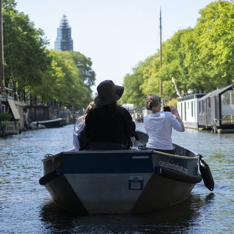 Mensen varen in bootje van Canal Motor Boats door de grachten van Amsterdam