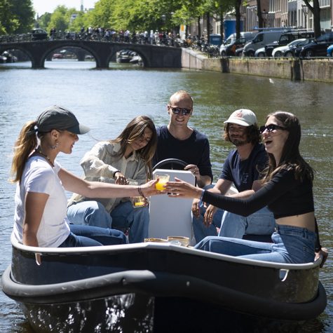 Mensen proosten in bootje op grachten in Amsterdam