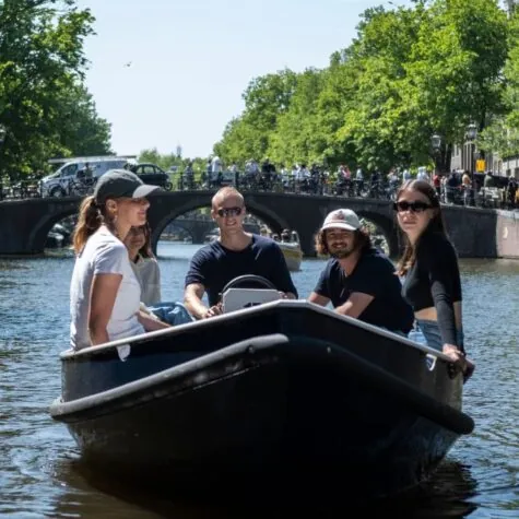 Een groep vrienden vaart door de grachten van Amsterdam op zelf varen boten.